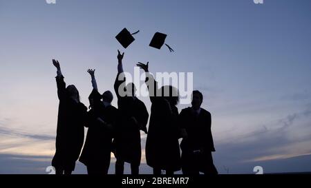 Silhouette of Graduating Students Throwing Caps In The Air. Stock Photo