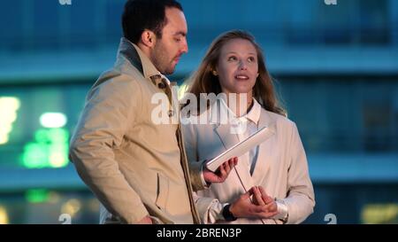 Two young work colleagues using a digital tablet while standing Stock Photo