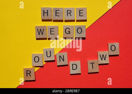 Here We Go, Round Two. Phrase in wooden alphabet letters on red and yellow background Stock Photo