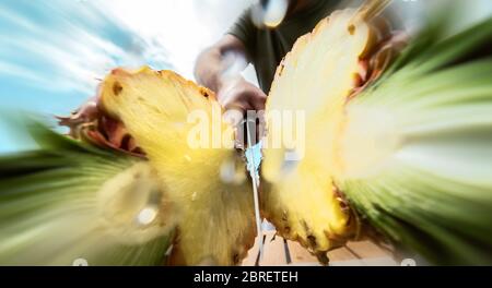 Portrait young man cutting pineapple - Close up male hand holding sharp knife preparing tropical fresh fruits Stock Photo