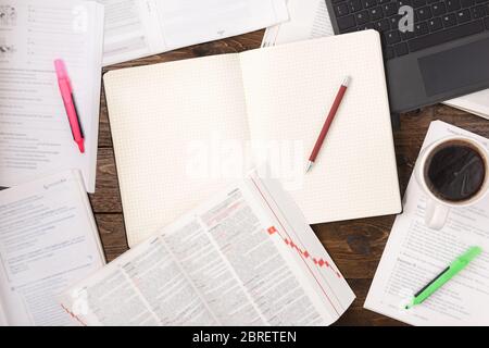 Remote education concept. Open books, smartphone, laptop, cup of coffe and blank notepad on wooden background. Flat lay, office working space Stock Photo