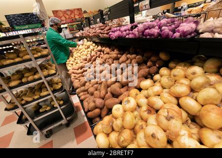 Man wearing protective mask restocking supermarket vegetable section Stock Photo