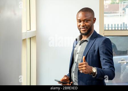 young african business man wearing a suit smiling and looking happy giving a thumbs up Stock Photo