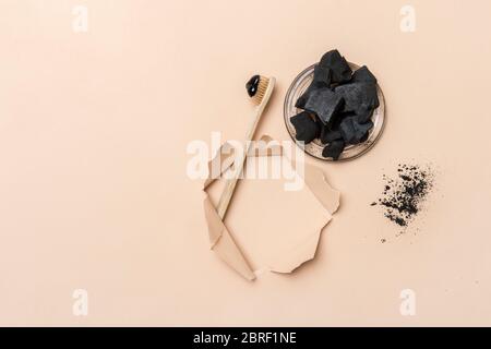 Natural toothpaste activated charcoal in glass jar and bamboo toothbrush on camel color background. Zero waste concept. Stock Photo