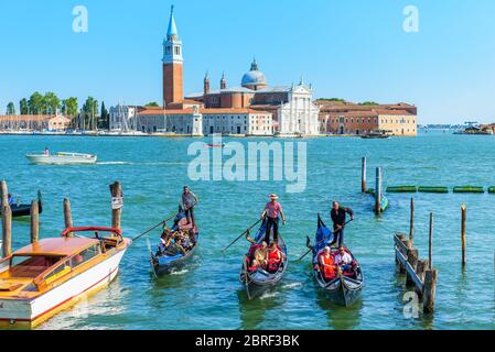 Venice, Italy - May 18, 2017: Gondolas with tourists are sailing along the Venetian lagoon. San Giorgio Maggiore in the background. The gondola is the Stock Photo