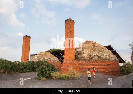 Two young Cambodian girls play together outside the beehive brick kilns. Battambang, Cambodia, Southeast Asia Stock Photo