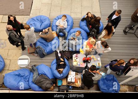 Young people relaxing on beanbags at the lounge zone Stock Photo