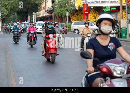 Ho Chi Minh, Vietnam - March, 1, 2020: Many Vietnamese people riding motorbikes motorcycles on road wearing masks Stock Photo