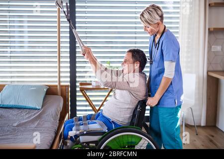 A healthcare worker and senior patient in wheelchair, physiotherapy. Stock Photo
