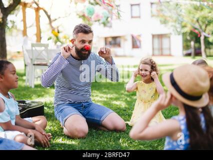 Man with small children on ground outdoors in garden in summer, playing. Stock Photo