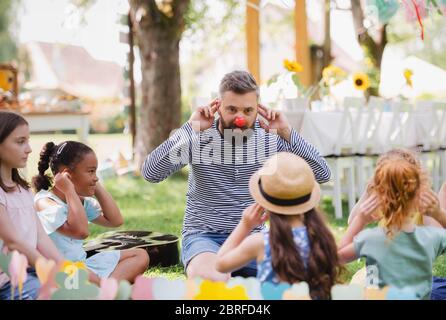 Man with small children on ground outdoors in garden in summer, playing. Stock Photo