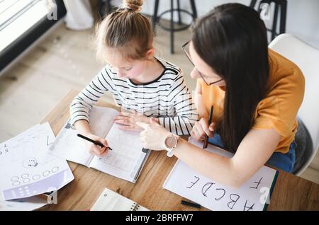 Mother and daughter learning indoors at home, corona virus and quarantine concept. Stock Photo