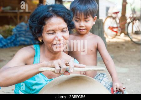 A woman makes a clay pot as a young boy looks on. Kampong Chhnang Province, Cambodia, Southeast Asia Stock Photo