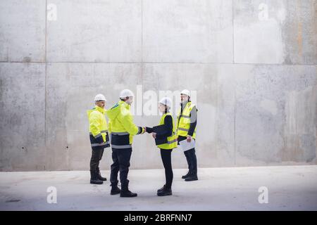 Group of engineers standing on construction site, shaking hands. Stock Photo
