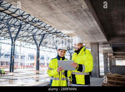 Engineers standing outdoors on construction site, using tablet. Stock Photo