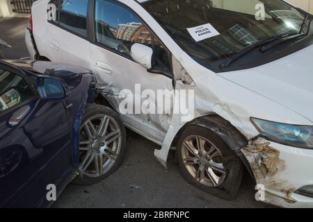 Car crash site in central London with two cars severely damaged from collision, with "Police Aware" notice in the windscreen of one of the cars Stock Photo