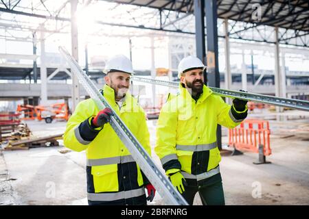 Men workers walking outdoors on construction site, working. Stock Photo