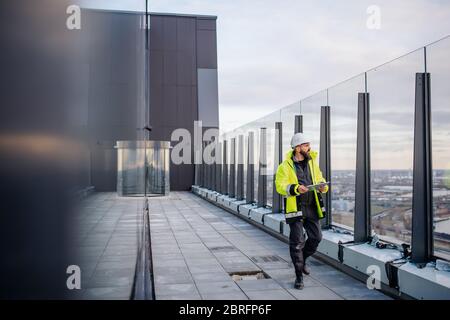 Man engineer walking on construction site, holding tablet. Stock Photo