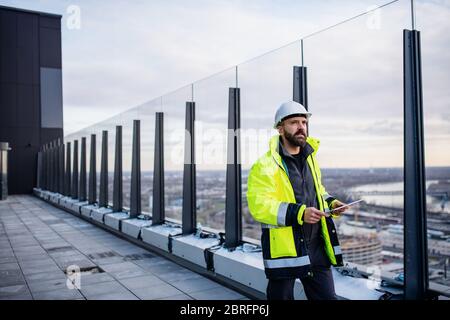 Man engineer walking on construction site, holding tablet. Stock Photo