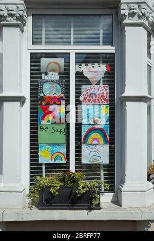Paintings of rainbows by children displayed in window of home to thank  NHS health staff and Key workers during the Covid-19 coronavirus pandemic Stock Photo