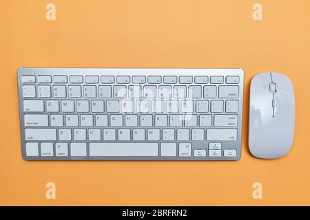 The keyboard and mouse are white on an orange table. Close up. Stock Photo