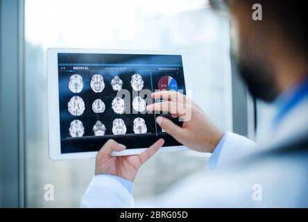 Unrecognizable doctor with tablet standing in hospital, working. Stock Photo