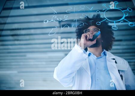 Doctor making notes in hospital, corona virus concept. Shot through glass. Stock Photo