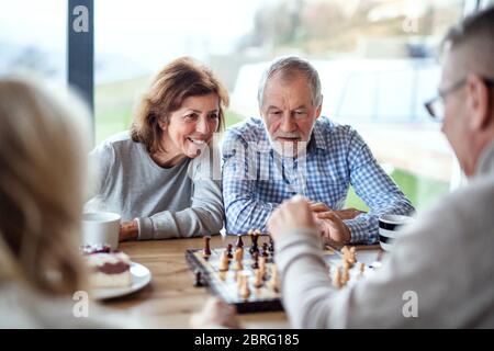 Group of senior friends at home, playing board games. Stock Photo
