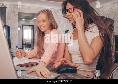Mother working from home with kids. Quarantine and closed school during coronavirus outbreak. Children make noise, disturb woman at work Stock Photo
