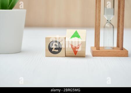 Wooden blocks with GBP pound sterling sign and up and down arrows. Close up. Stock Photo