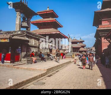 Nepal, Kathmandu. Coulrful street scenes in the medieval Durbar Square of Patan looking towards the memorial column to King Yoganarendra Malla the Shiva Temple and Teluju Bell Stock Photo