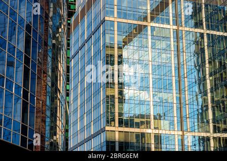 Abstract architecture background. Sky and buildings are reflected in facades of dense office skyscrapers. Steel and glass urban style close-up. Concep Stock Photo
