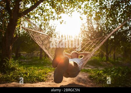 blurry and defocus relaxing in hammock. man rest in garden. summer vibes in forest Stock Photo
