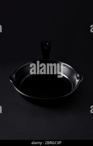 Empty black frying pan on black background Stock Photo