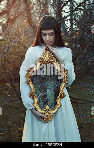 Woman holding strange mirror in sunset light Stock Photo