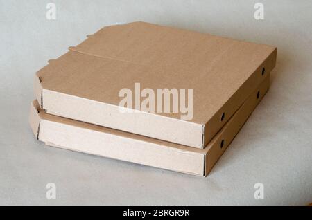 Cardboard boxes for pizza close-up. Two closed brown boxes in a stack. Food packaging and delivery. Courier service. Close-up. Selective focus. Stock Photo
