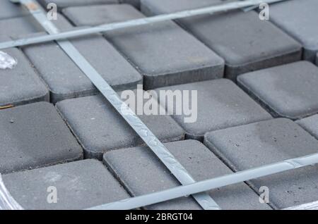 Packing gray new paving slabs with clouse up. Cement tile set by a become bondana tape with raindrops. Construction Materials. Selective focus. Stock Photo