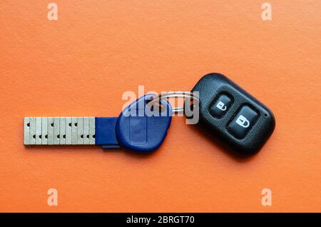 Chipped door key with remote control on an orange background .. Innovative key with a unique secret combination. Modern technologies for the protectio Stock Photo