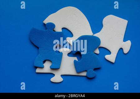 Blue background with two-color puzzle pieces. Blue and white unconnected fragments. Search and removal of excess. View from above. Stock Photo