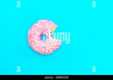 Top view of bitten glazed donut on blue background with copy space Stock Photo