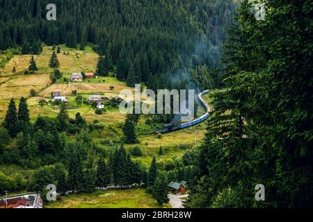 A long train in the mountains of the Carpathians. Bright landscape and train. Stock Photo