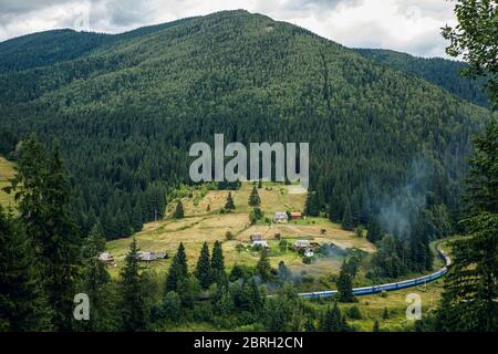 A long train in the mountains of the Carpathians. Bright landscape and train. Stock Photo