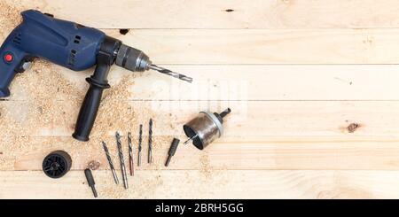 Top view of drill, drill bits and joinery accessories on natural pine wood workbench. Space for text. Work and DIY concept. Stock Photo