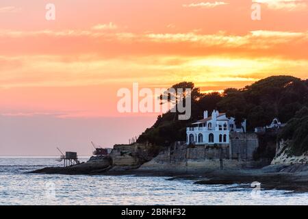 Saint-Palais-sur-Mer, France: Traditional fishing huts and a luxurious villa with a sea view built on the coast near to the town centre, at sunset. Stock Photo
