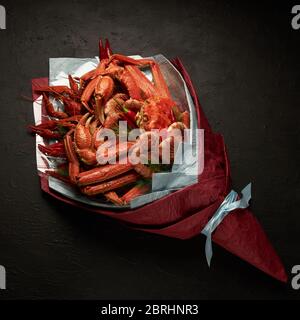 Beautiful unusual packaging of seafood in the form of a bouquet on a black background. Stock Photo