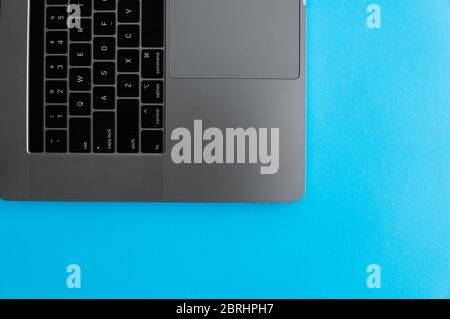 Keyboard of a silver laptop that lying on a blue background Stock Photo