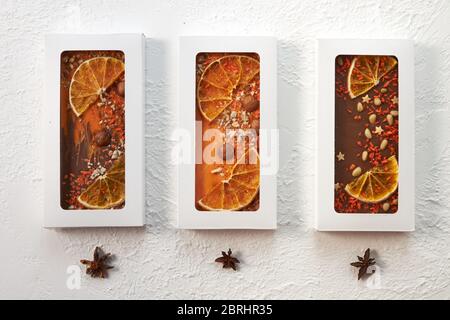 Three handmade chocolate bars with nuts and dried fruits on a white background. Stock Photo