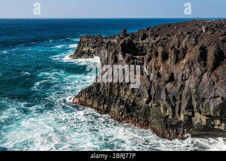 Tourists visiting 'Los Hervideros', a popular tourist attraction, bizarre-shaped cliffs and underwater caves formed by lava solidification and erosion. Stock Photo