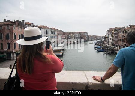 VENICE, ITALY - MAY: Tourists take pictures from Rialto Bridge on May 18, 2020 in Venice, Italy. Restaurants, bars, cafes, hairdressers and other shop