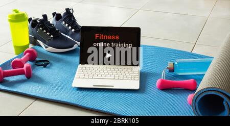 Fitness sports equipment and laptop on gray cement background. Home online workout concept. Fitness online training. Stock Photo